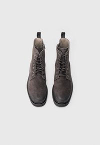 Bottes bottines en daim gris à finition lisse, dotées d'œillets métalliques, de lacets et d'une fermeture éclair latérale pour un enfilage facile. Semelles en caoutchouc noir durables.