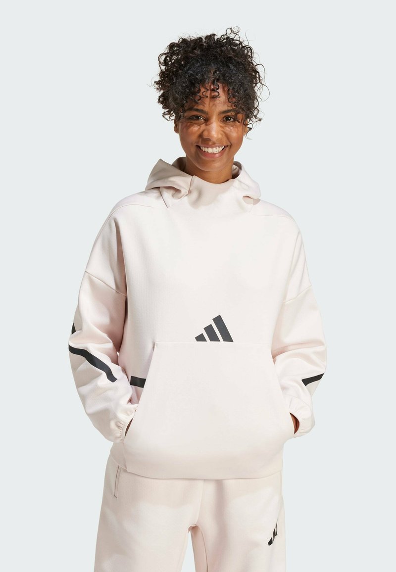 Light pink hooded sweatshirt with a kangaroo pocket, featuring black Adidas stripes on sleeves and logo on the front. Soft texture.