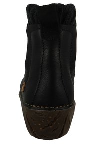 Black leather boot with a textured upper, round toe, and a durable brown sole. Features stitching accents and a small pull tab at the back.