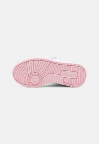 Fehér sneaker talp rózsaszín gumibetéttel; textúrált talpmintázatokkal, kör alakú dizájn elemekkel és egy logóval az oldalon.