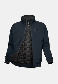 Chaqueta azul marino con cierre de cremallera, cuello alto, forro acolchado negro y puños elásticos, con un logo en el pecho y un exterior suave.