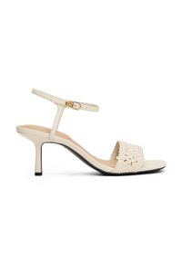 Sandale à talons hauts beige avec une sangle tissée, sangle de cheville réglable avec boucle en or, semelle lisse et design à bout pointu.