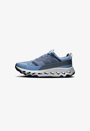 Blue athletic shoe with textured mesh upper, contrasting dark accents, thick white midsole with cutouts, and padded collar for comfort.