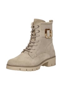 Beige suède enkellaars met vetersluiting aan de voorkant, chunky zool en decoratieve schildpaddenschildgesp aan de zijkant.