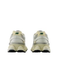 Weiße und cremefarbene Sneaker mit strukturiertem Finish, silbernen Akzenten und einer dunklen Gummisohle. Merkmale sind grüne Markenbeschriftungen an der Ferse.