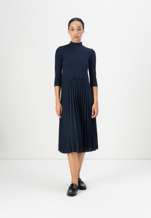 Navy blue dress with a ribbed bodice, three-quarter sleeves, and a pleated skirt. Features a drawstring at the waist and falls below the knee.
