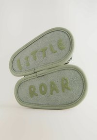 Ljust gröna tofflor med mocka yta, som har orden "liten" och "vrål" broderade med mjuka gröna bokstäver på sulorna.