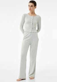 Lys grå loungewear sæt med ribbet tekstur, lange ærmer, rund hals, knaplukning og elastisk talje med flared bukser.