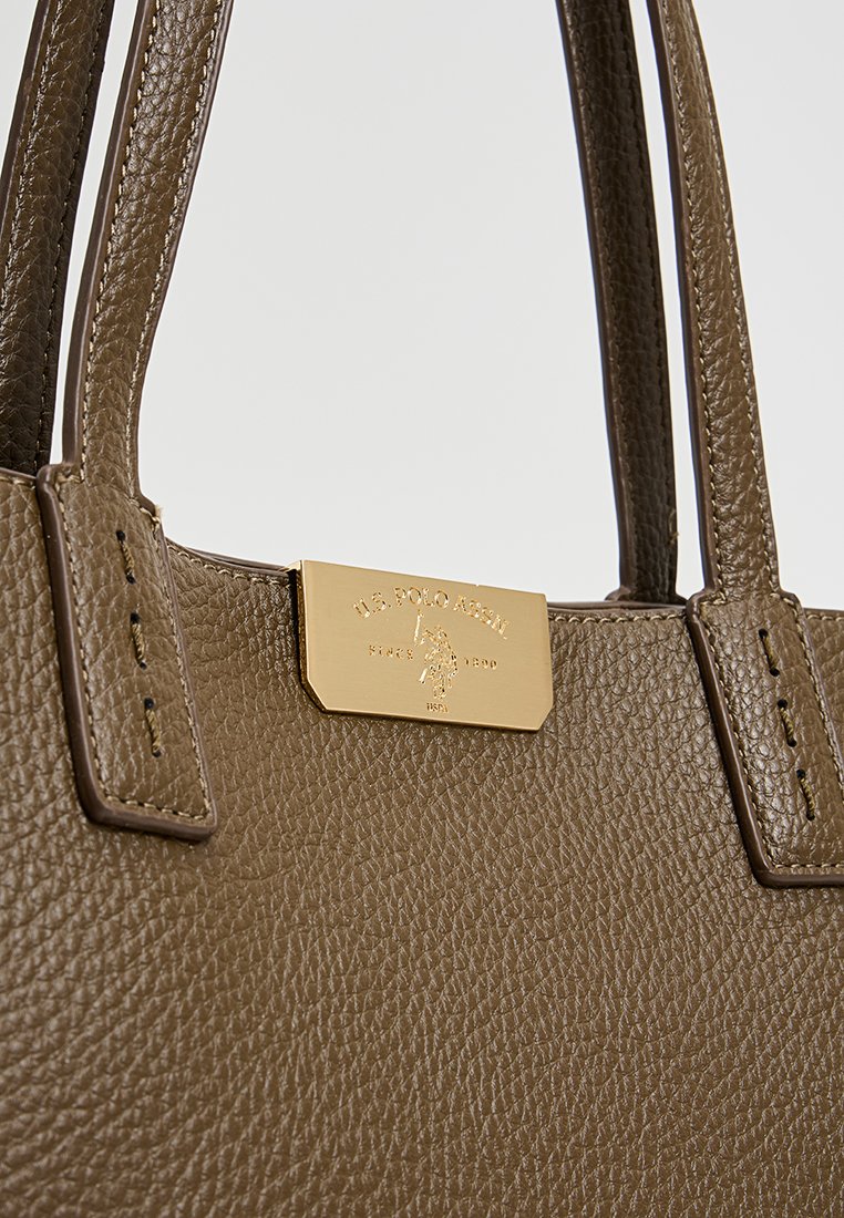Bolso tote de cuero marrón con superficie texturizada, que presenta asas cortas y una placa de logo dorado en relieve como detalle destacado.
