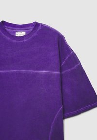 T-shirt viola a maniche corte realizzato in tessuto morbido, con scollatura rotonda, cuciture tono su tono e una vestibilità rilassata con una sottile texture.