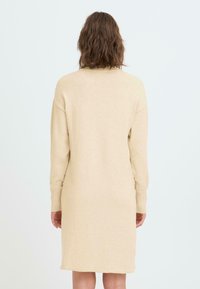 Abito sportivo in maglia beige con maniche lunghe, polsini a costine e vestibilità comoda. Tessuto liscio e lunghezza sopra il ginocchio. Design semplice senza pattern.