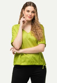 Top s krátkým rukávem ve tvaru V v jasně limetkově zelené barvě, vyrobený z lehkého materiálu, s nařaseným lemem a detailem zavazování.