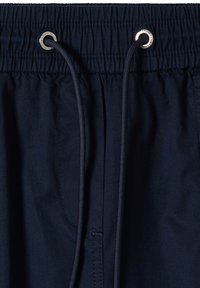 Ceinture élastique bleu marine avec cordon assorti passant à travers des œillets métalliques argentés sur un short ou un pantalon en tissu.