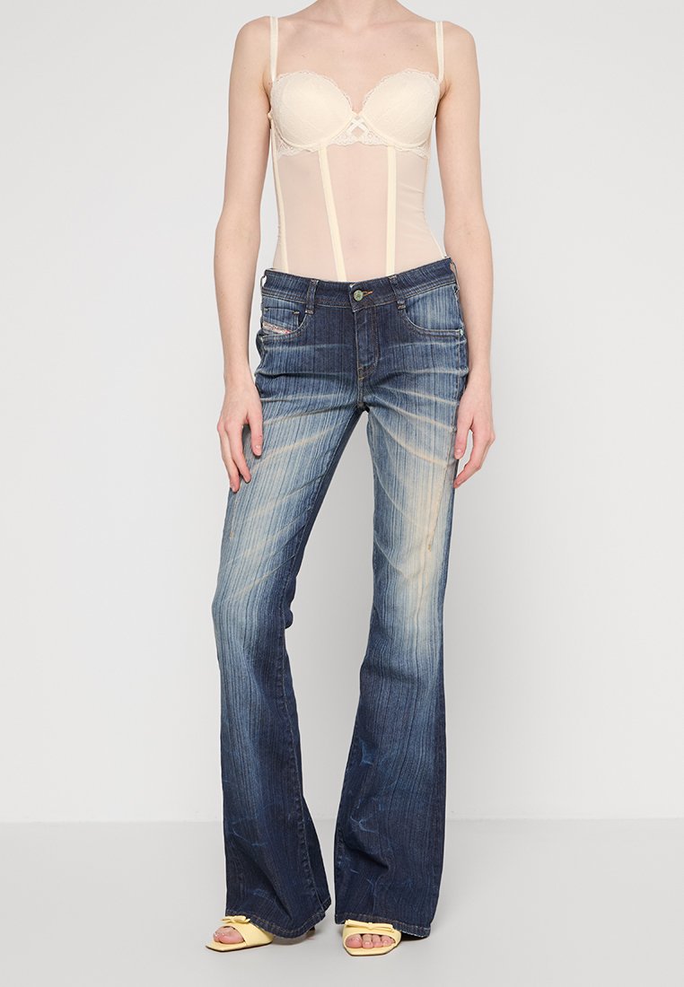 Denim Schlagjeans mit einem hellblauen Verlauf, der eine leichte Ausbleichung und subtile Abnutzungsspuren aufweist. Gerader Schnitt mit fünf Taschen und metallischen Akzenten.