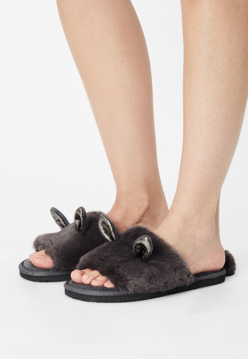 Grey fur slide slippers with black textured soles, featuring shiny silver ear accents for detail. Open-toed design, soft and plush material.