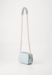 Light blue leather crossbody bag with a rectangular shape, chain and fabric strap, and double zipper closure. Smooth texture, minimal design.