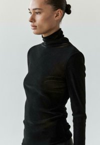 Czarny, długi rękaw z golfem wykonany z miękkiej, teksturowanej tkaniny, charakteryzujący się dopasowanym krojem i minimalistycznym designem.