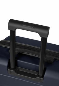 Maleta con ruedas azul marino con exterior texturizado, asa retráctil negra y cierre de cremallera. Cuenta con una base moldeada para mayor estabilidad.