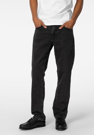 Sorte denim jeans med rett ben design, som har frontlommer og en teksturert finish, kombinert med svarte sko. Hvit t-skjorte synlig.