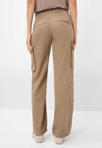 Khaki cargobroek met een losse fit, voorzien van twee zijzakken, achterzakken en gestikte details langs de naden. Glad stofgevoel.
