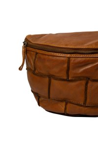 Borsa in pelle marrone con cuciture a patchwork e una cerniera chiusa, mostrata su uno sfondo bianco.