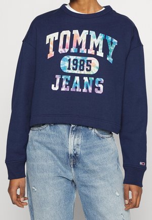 Marinblå croppad sweatshirt med "TOMMY JEANS"-logotyp i flerfärgad gradient, med ribbade ärmslut och en vit lagerkrage under.