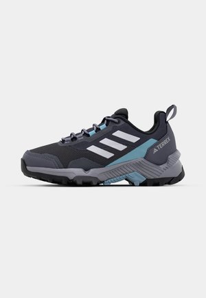 Schwarzer und grauer Sportschuh mit blauen Akzenten, Mesh-Obermaterial, drei weißen Streifen, strukturiertem Zwischensohlenteil und robuster schwarzer Außensohle.