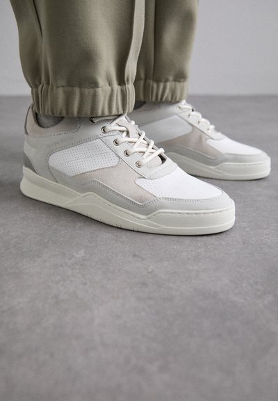 White and light gray sneakers featuring a textured upper, lace closure, and a padded collar. The design includes perforated and suede accents.