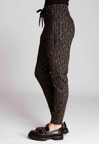 Schwarze Jogginghosen mit geometrischem Goldmuster, elastischem Taillenbund mit Kordelzug, seitlichen Taschen und schmal zulaufendem Beindesign. Strukturierter Stoff.