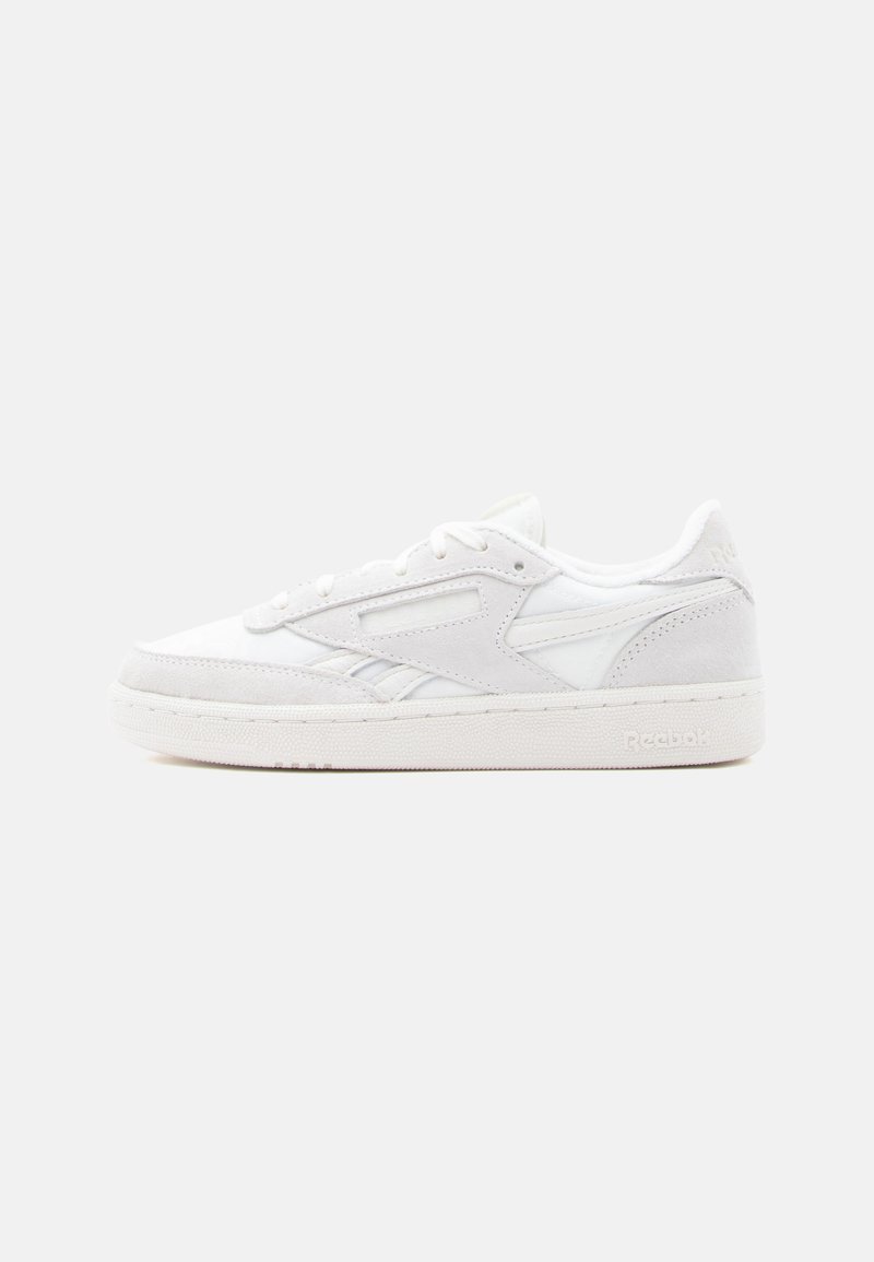 Baskets basses blanches Reebok avec superpositions en daim, lacets et semelle en caoutchouc texturée sur un fond clair uni.