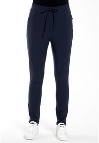 Marine joggerbroek van rekbare stof, met een elastische tailleband, trekkoordsluiting en taps toelopende benen. Witte sneakers maken de look compleet.
