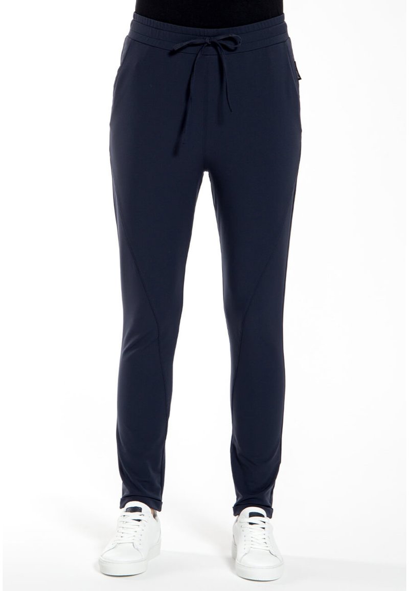 Marine joggerbroek van rekbare stof, met een elastische tailleband, trekkoordsluiting en taps toelopende benen. Witte sneakers maken de look compleet.