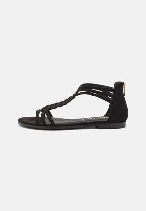 Flad sort sandal med flettet frontrem, flere tynde sideremme og en lynlåslukning bag på hælen.