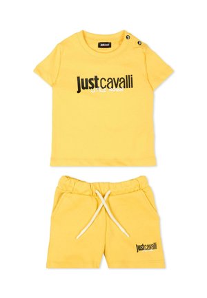 Completo giallo per bambino con maglietta a maniche corte e pantaloncini, entrambi con il logo "Just Cavalli Little Rogue" in testo nero e bianco.