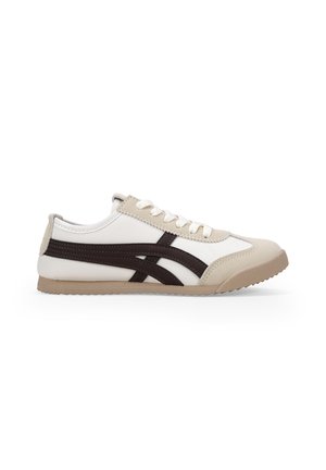 Zapatilla con parte superior blanca y beige, acentos marrones, punta redondeada y cordones planos. Presenta una suela de goma texturizada y un diseño deportivo.