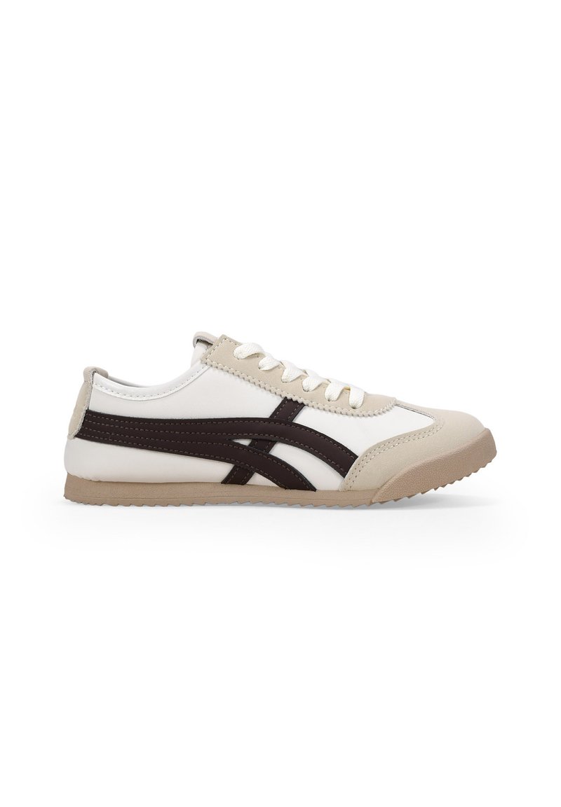 Zapatilla con parte superior blanca y beige, acentos marrones, punta redondeada y cordones planos. Presenta una suela de goma texturizada y un diseño deportivo.