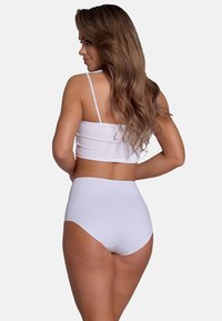 Crop top blanc avec de fines bretelles et un bas taille haute, tous deux en tissu lisse, présentant un design sans couture et un style minimaliste.