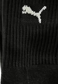 Black ribbed fabric displaying a white Puma logo in the shape of a leaping cat.
