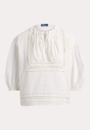 Weiße Bluse mit langen Ärmeln, quadratischen Spitzenakzenten, gerafftem Ausschnitt mit Bindeschluss und elastischen Manschetten.