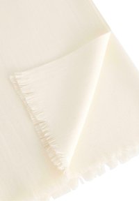 Světle krémová šála, měkká textura, se třásněmi na okrajích a jednoduchým, nenápadným designem. Vhodná pro vrstvení nebo k přidání tepla.