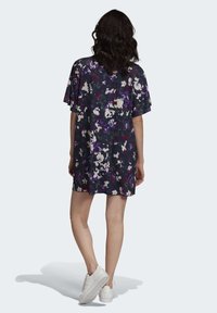 Květinový vzorovan�ý krátký šat v tmavě námořnické barvě s fialovými a krémovými akcenty. Vyrobeno z lehké tkaniny, má krátké rukávy a volný střih.