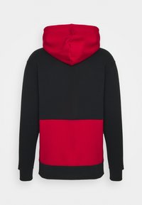 Vue de dos d'un sweat à capuche avec une capuche rouge, le haut du corps noir et le bas rouge, avec de longues manches noires et des poignets en côtes.