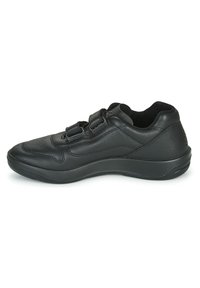 Chaussure de sport en cuir noir avec un bout arrondi, une tige texturée et des sangles ajustables pour la fermeture. Semelle rembourrée et design élégant.