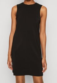 Sorte ærmeløs kjole lavet af et glat, let stof. Enkel, tætsiddende design med rund halsudskæring og ingen yderligere pynt.