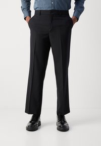 Czarne, dopasowane spodnie o prostych nogawkach, gładka faktura tkaniny oraz przednie kieszenie. W zestawie z czarnymi butami sznurowanymi.