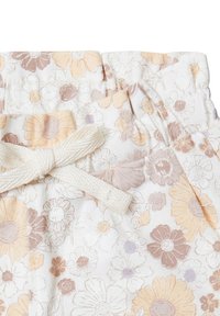 Bloemmotief broek van zacht wit stof, met bloemen in perzik en mauve, een gerimpelde taille en een zachte touwtjesluiting.