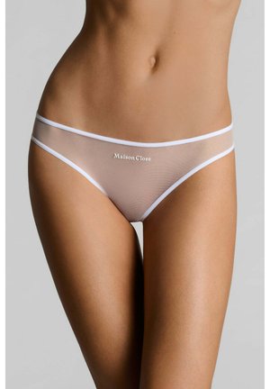 Gros plan d'une personne portant un sous-vêtement style bikini beige transparent avec une bordure blanche et le texte "Maison Close" au centre avant.