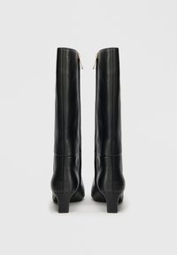 Schwarze Leder-Stiefel bis zum Knie mit runder Zehe, mittelhohem Blockabsatz und hinterem Reißverschluss, die eine glatte Textur und eine figurbetonte Passform aufweisen.