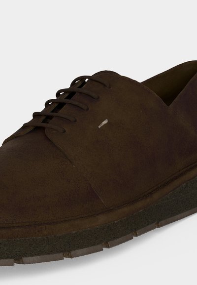 Σκούρο καφέ κλειστό παπούτσι από σουέτ με μαύρη υφασμάτινη σόλα, ορατά ραφές και χαμηλό προφίλ.