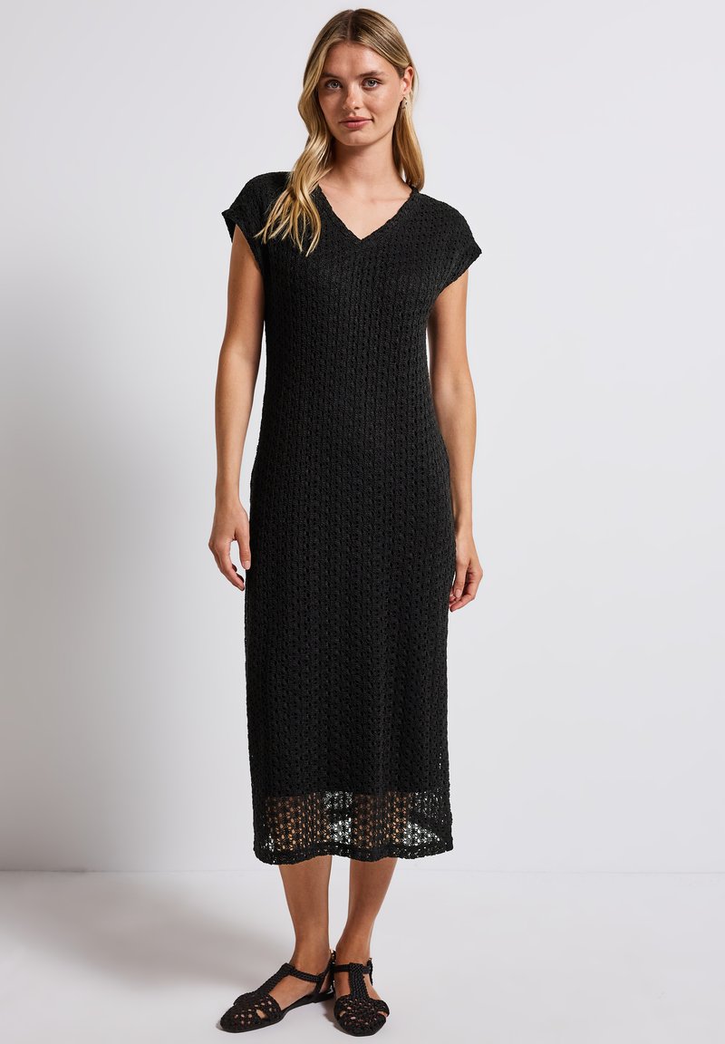 Abito midi lavorato a maglia di colore nero con scollatura a V, maniche corte e vestibilità ampia. Presenta un motivo a trama aperta e arriva all'altezza del polpaccio.